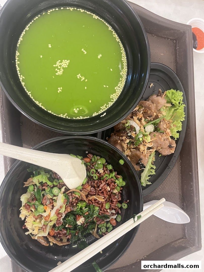 A close-up of a healthy meal with brown rice, vegetables, meat, and a green drink.