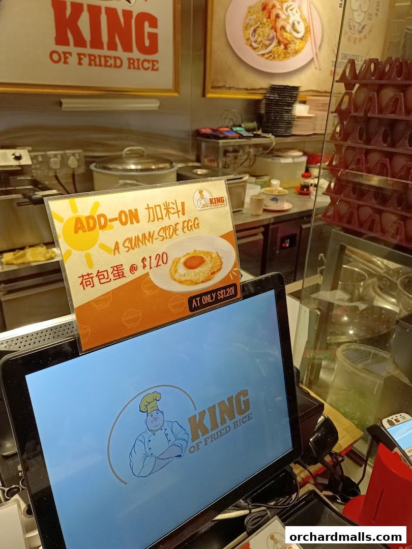 A close-up of a counter at King of Fried Rice, showing an add-on menu for a sunny-side egg.