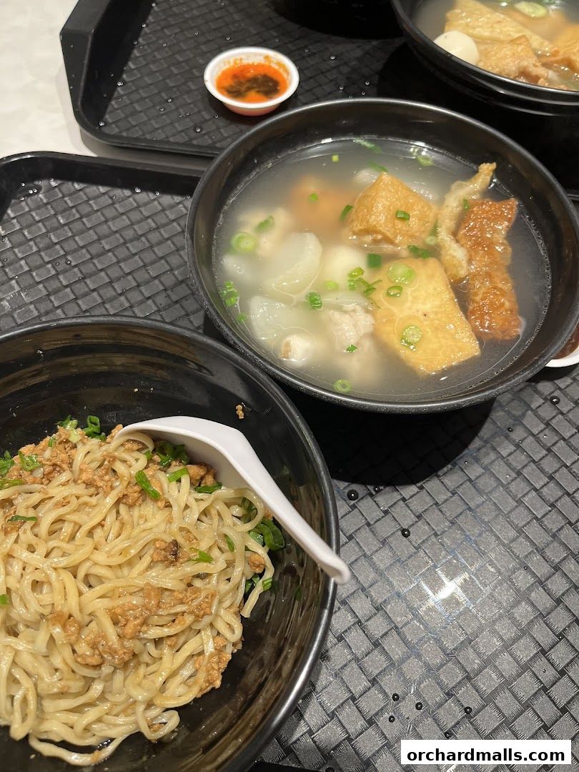 Two bowls of noodles and soup with various ingredients, served on a tray.