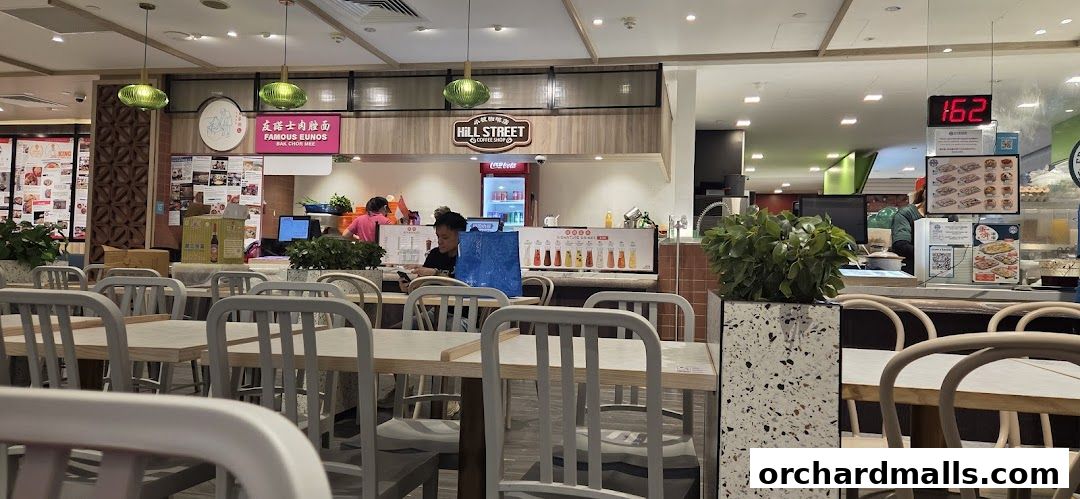 Interior view of a food court stall with seating and a counter displaying food items.