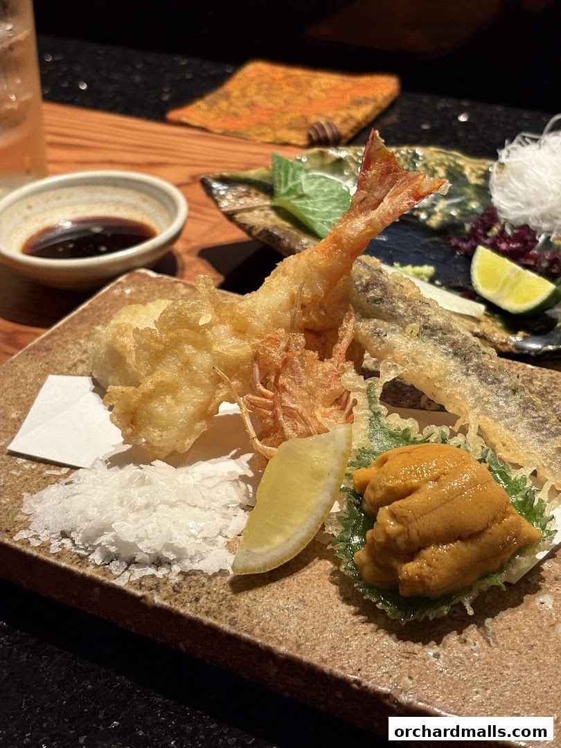 A plate of tempura, uni, and a fish with lemon and dipping sauce.