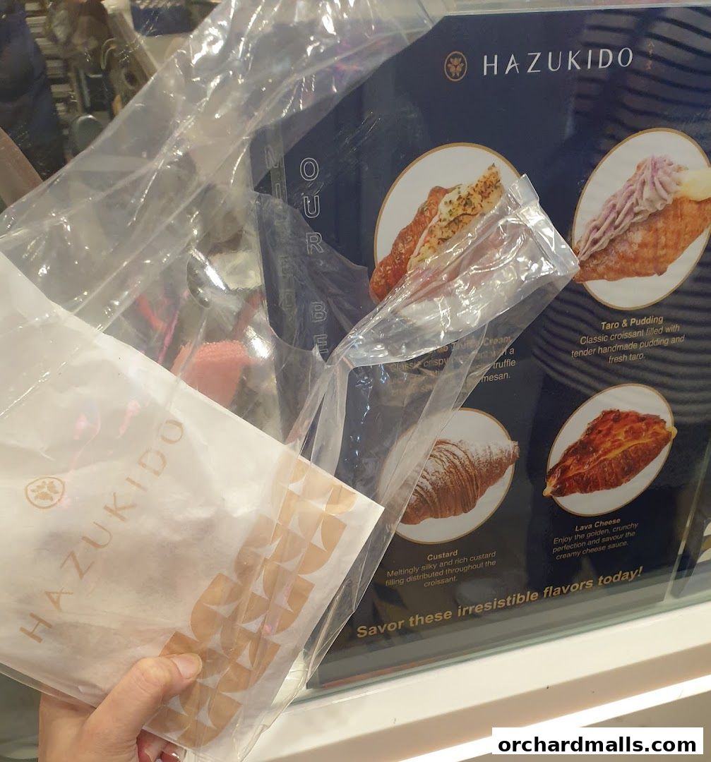 A display board showcasing various croissant flavors from Hazukido.