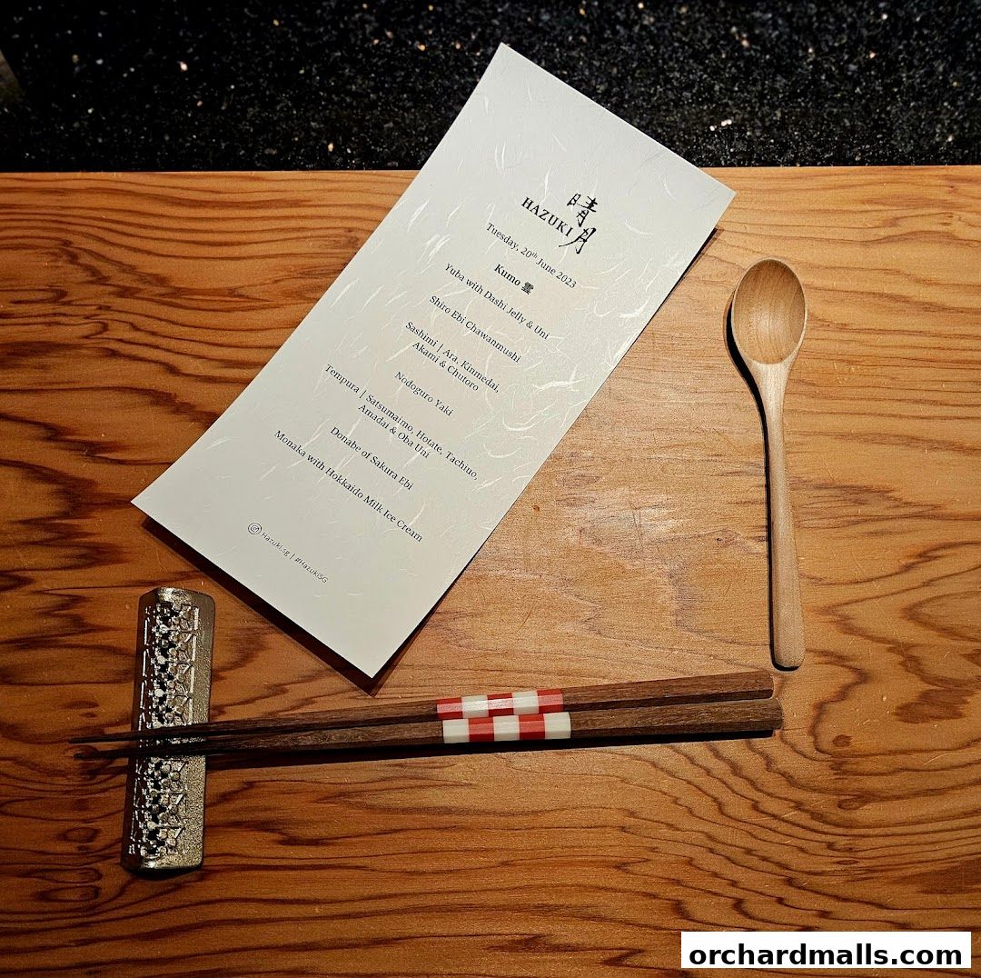 A menu from Hazuki restaurant with Japanese dishes and a wooden spoon and chopsticks.