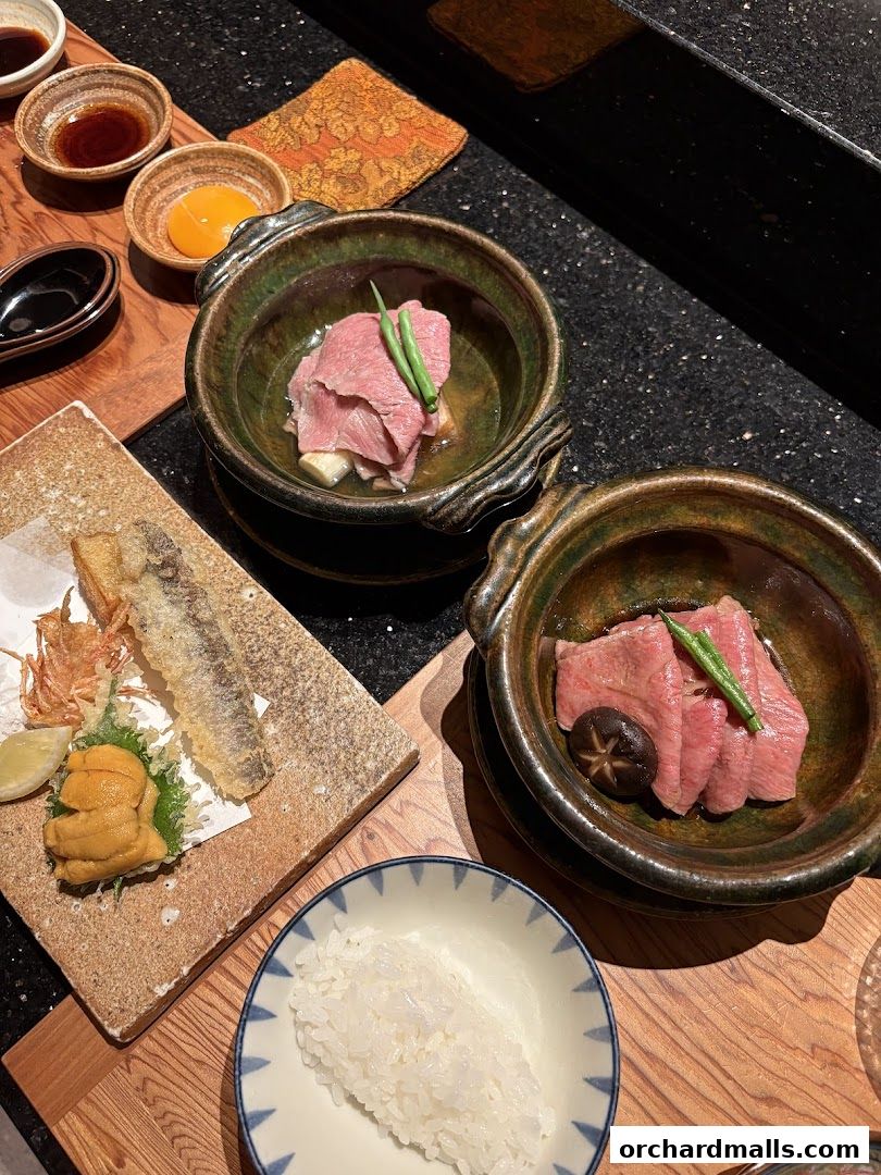 A beautifully presented Japanese meal featuring tempura, uni, rice, and braised beef.