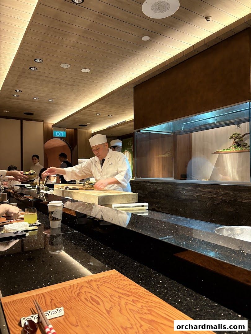 A sushi chef prepares food at a counter in a modern restaurant.