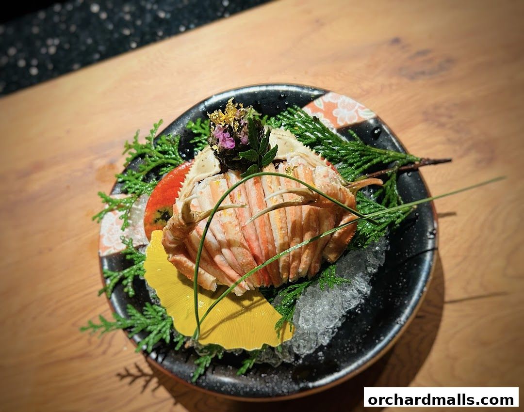 A beautifully presented crab dish with garnishes on a black plate.