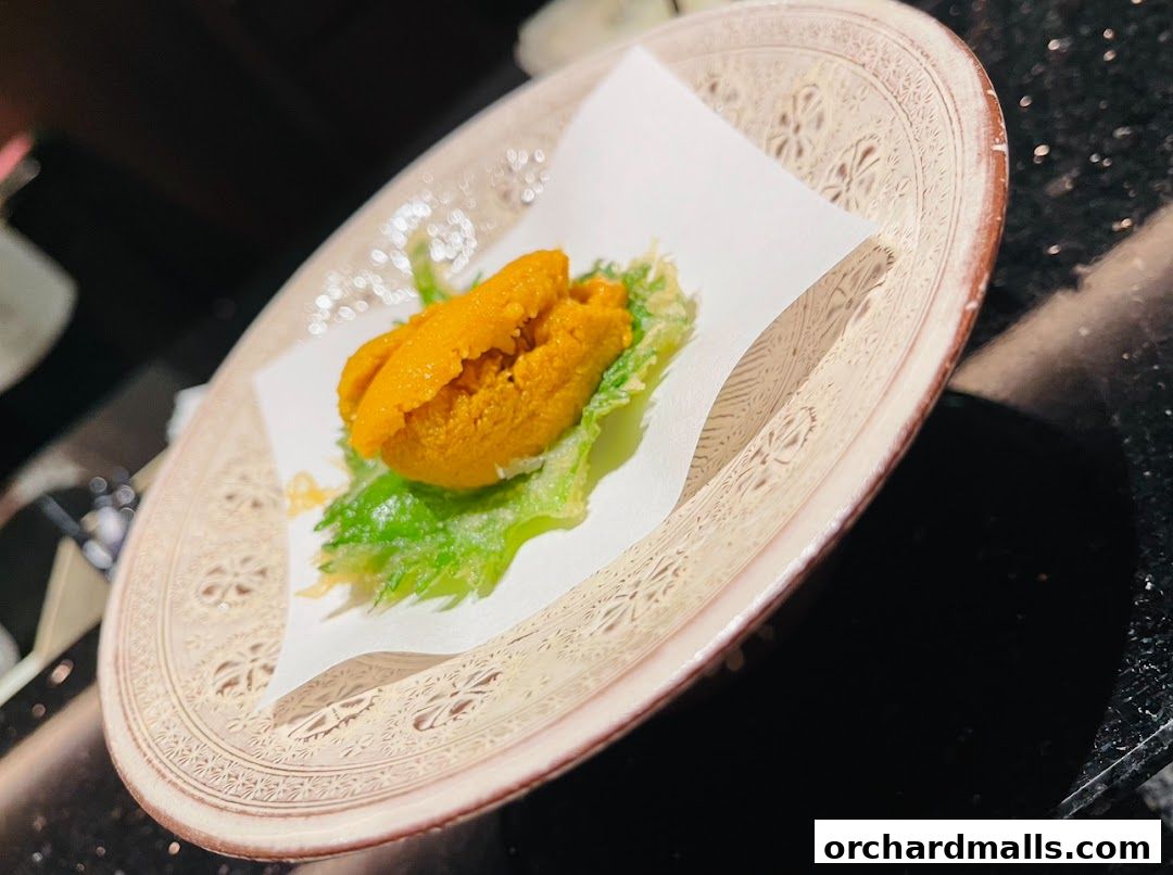A close-up of a delicate uni (sea urchin) dish served on a decorative plate.