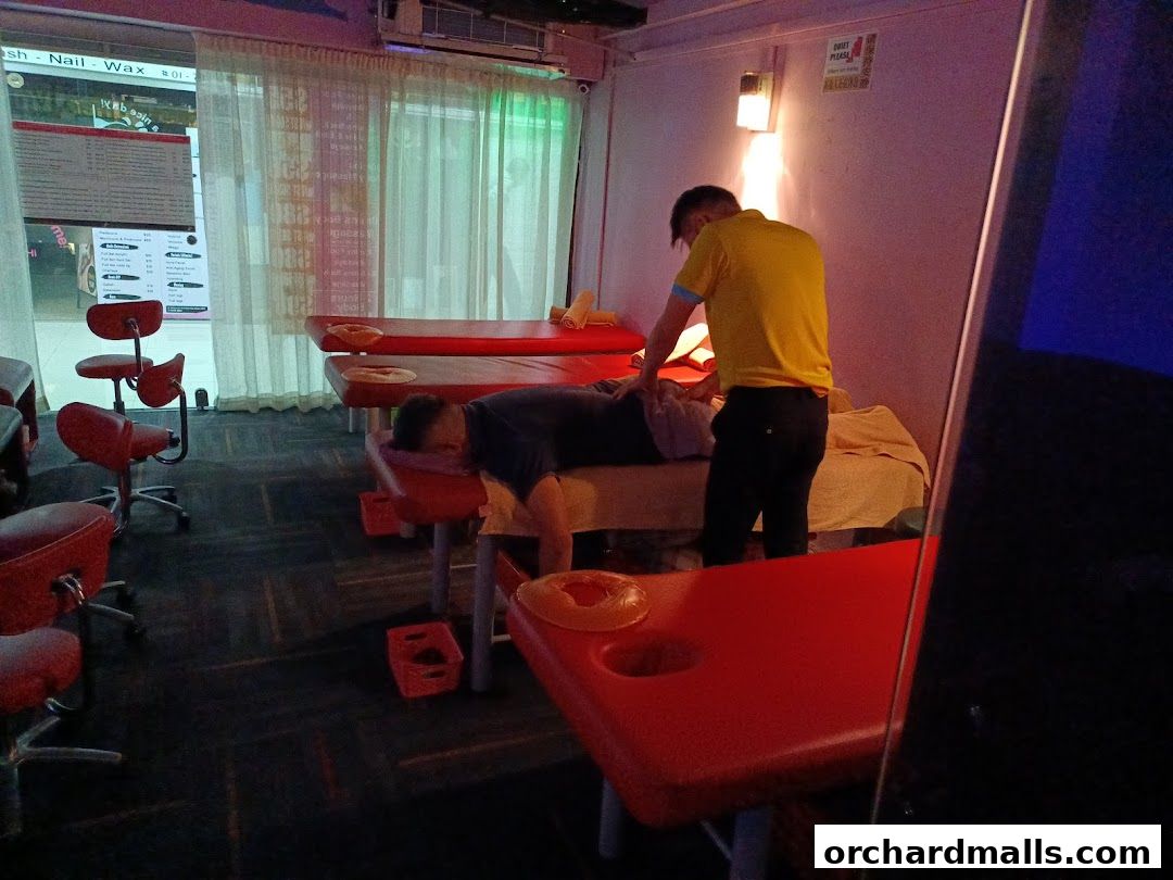 A person receiving a foot massage at Herbal Footcare with multiple massage beds.
