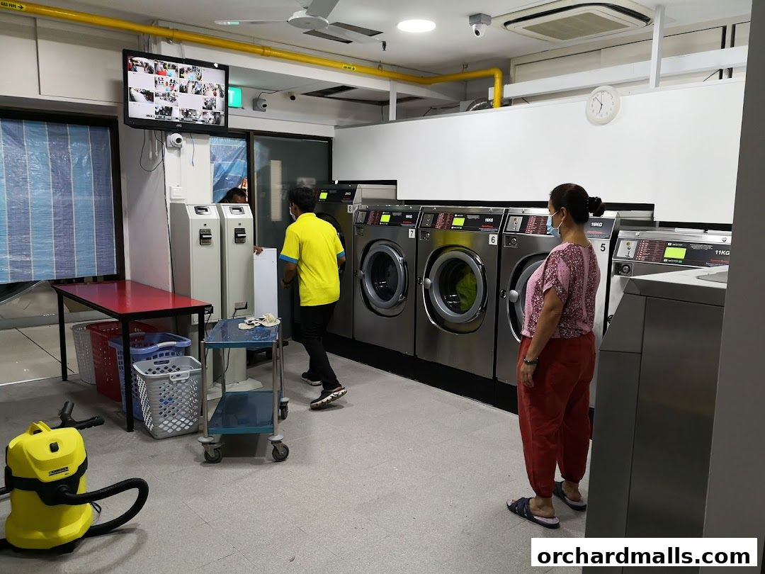 Interior of a self-service laundry with washing machines, dryers, and customers.