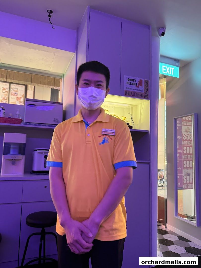 A staff member in a yellow polo shirt stands in front of a counter at Herbal Footcare.