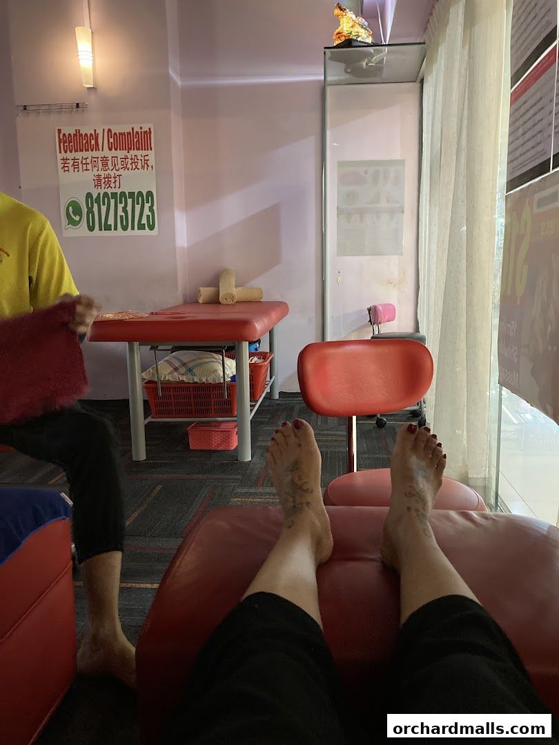 A person's feet resting on a red recliner in a foot care shop.