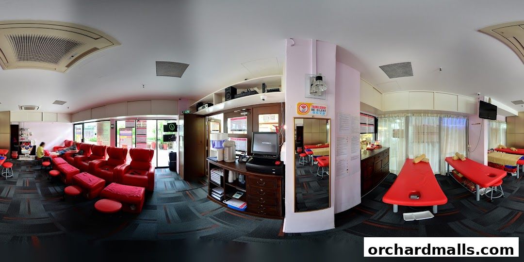 Interior of a foot care and massage shop with red recliners and massage beds.