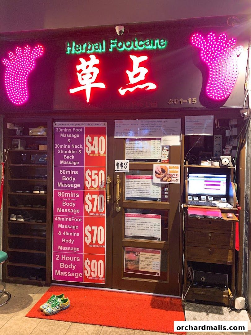 The entrance of Herbal Footcare shop with neon signs, service promotions, and a computer station.