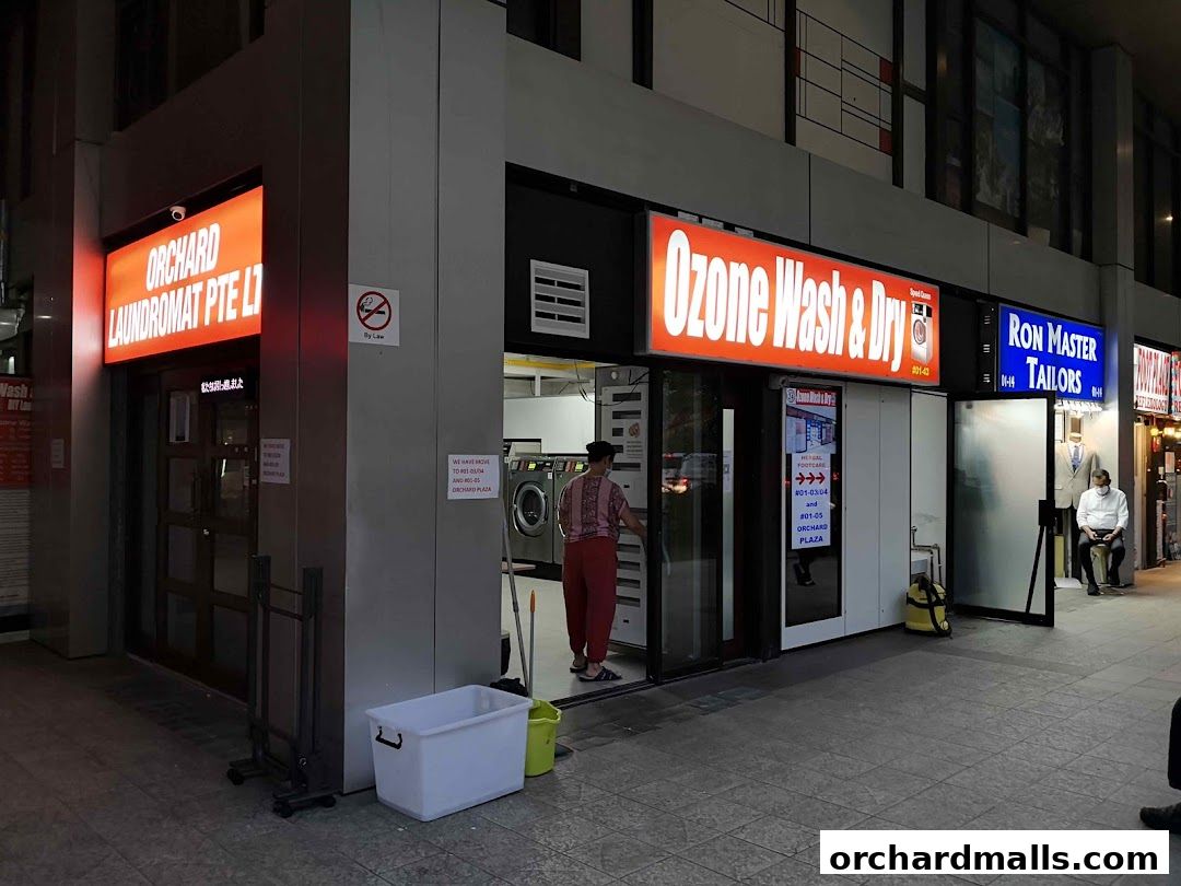 Exterior view of multiple shops including a laundromat and a tailor.