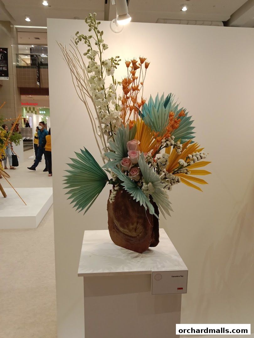 A striking floral arrangement with dried elements and roses displayed on a pedestal.