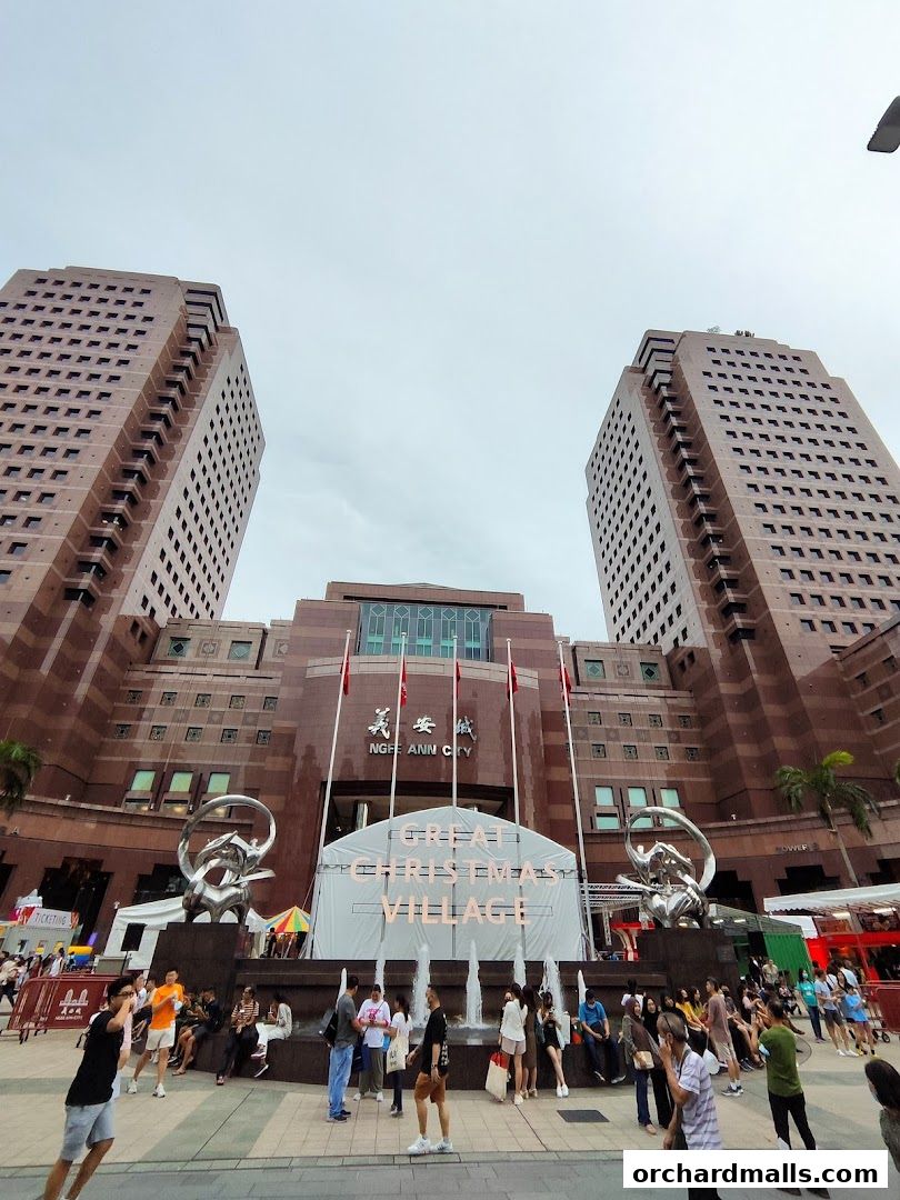People gather in front of Ngee Ann City, with a 'Great Christmas Village' setup.