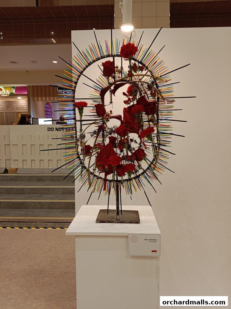 A striking floral arrangement with red roses and carnations, displayed on a pedestal.