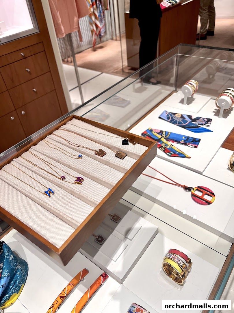 Display of Hermès jewelry and accessories, including necklaces, rings, and scarves.
