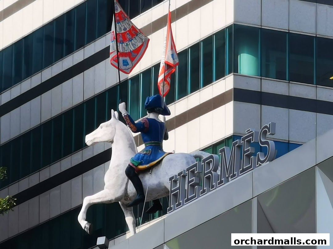 Hermès Singapore Takashimaya storefront with a statue of a rider on a horse and flags.