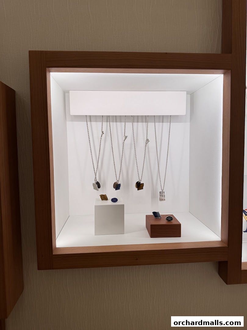 A display case showcasing Hermès necklaces and rings with gemstone pendants.