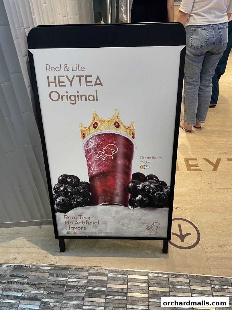 A sign for HEYTEA Original featuring a grape-themed drink with a crown and grapes.