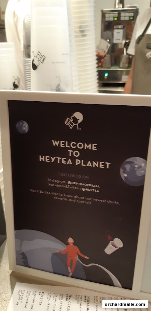 A welcome sign for HEYTEA Planet with social media handles and a space-themed illustration.