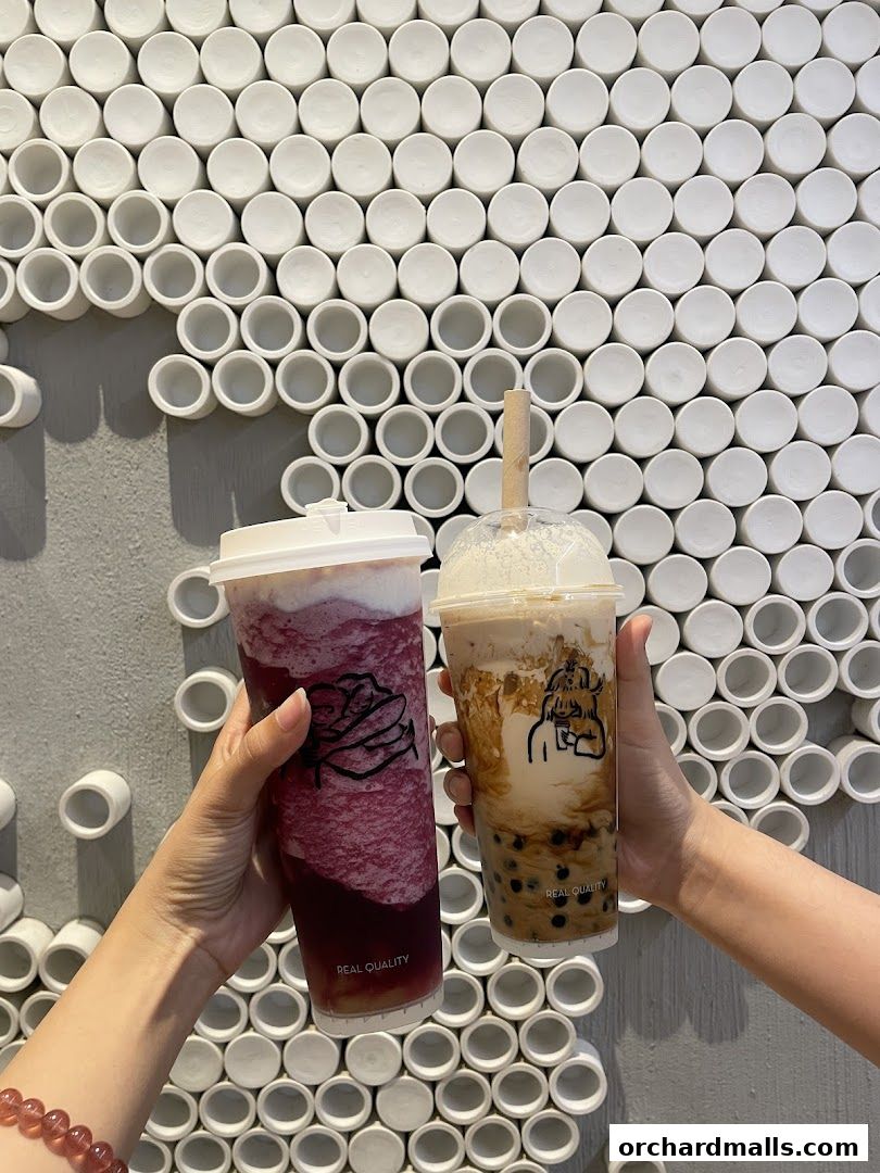 Two hands hold up refreshing bubble tea drinks against a textured white wall.