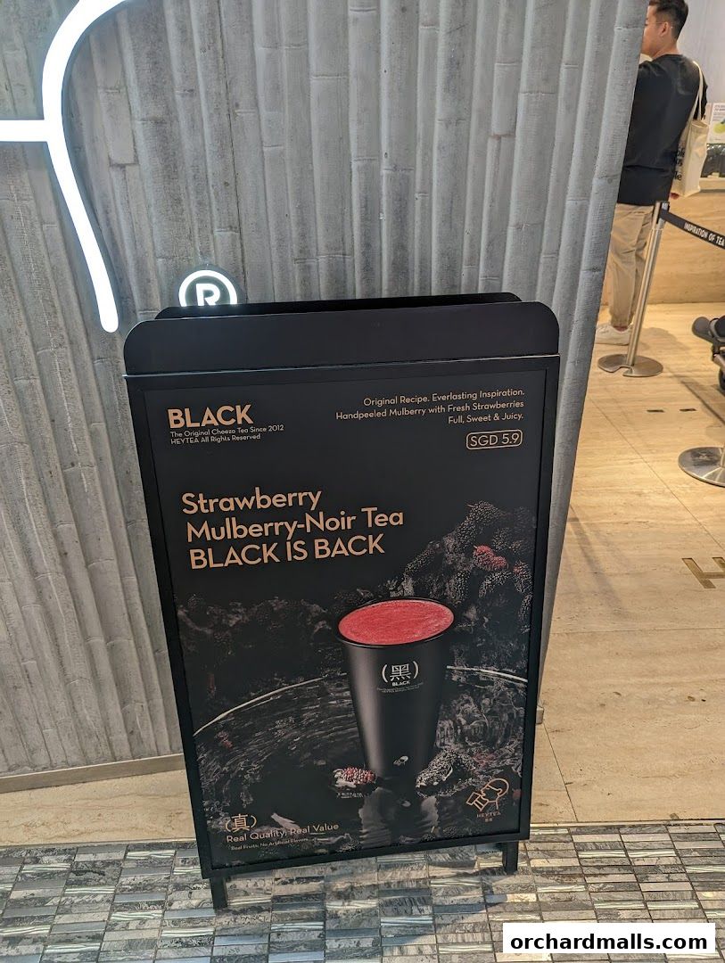 A promotional sign for HEYTEA's Strawberry Mulberry-Noir Tea, featuring a cup and ingredients.