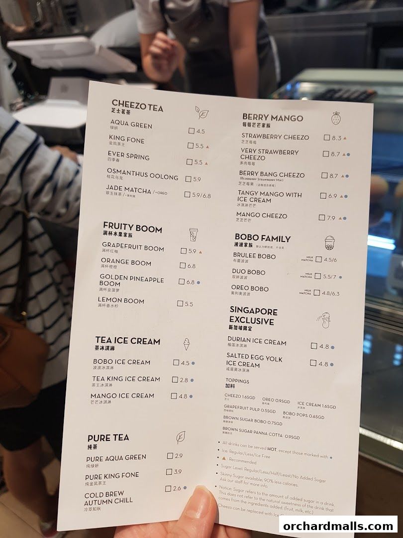A hand holds a menu from HEYTEA, showcasing various tea and ice cream options.