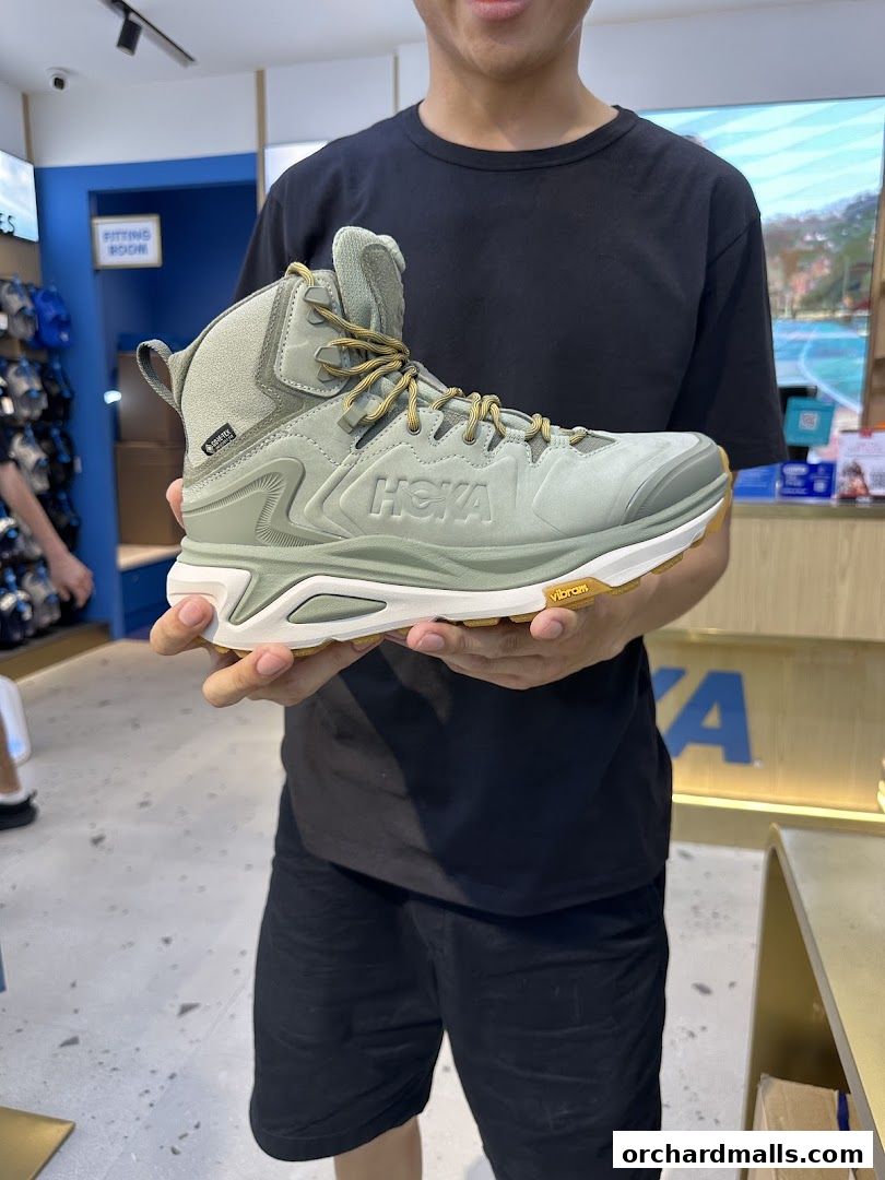 A person holds up a Hoka hiking boot inside a Hoka store.