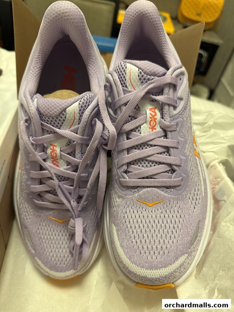 A pair of new, light purple HOKA running shoes in a box.