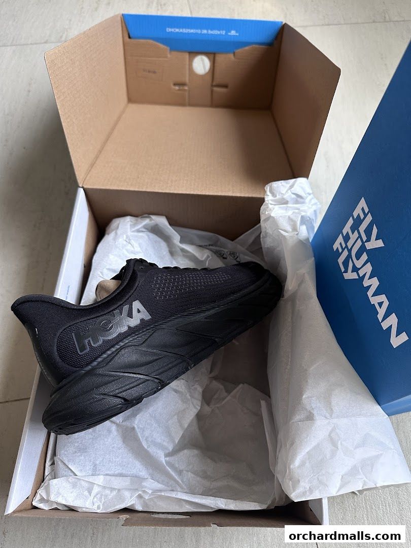 A black HOKA running shoe is unboxed, ready for adventure.