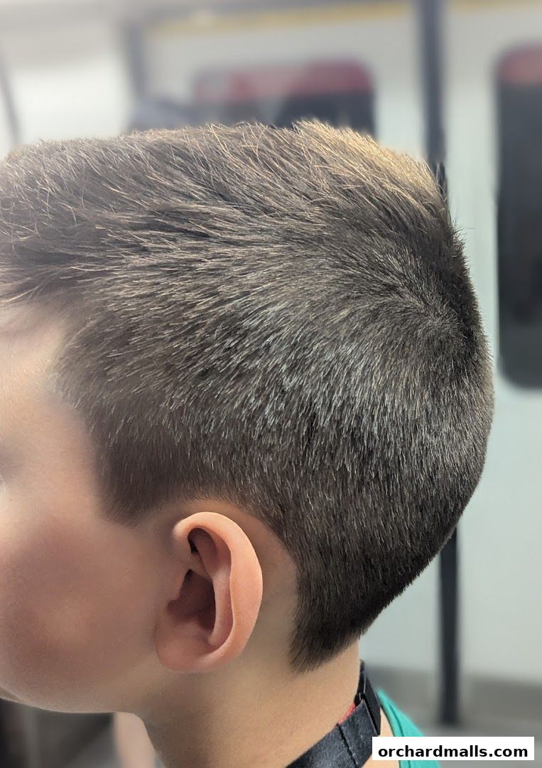 Close-up of a neat haircut on a young person's head, showing the side and back.