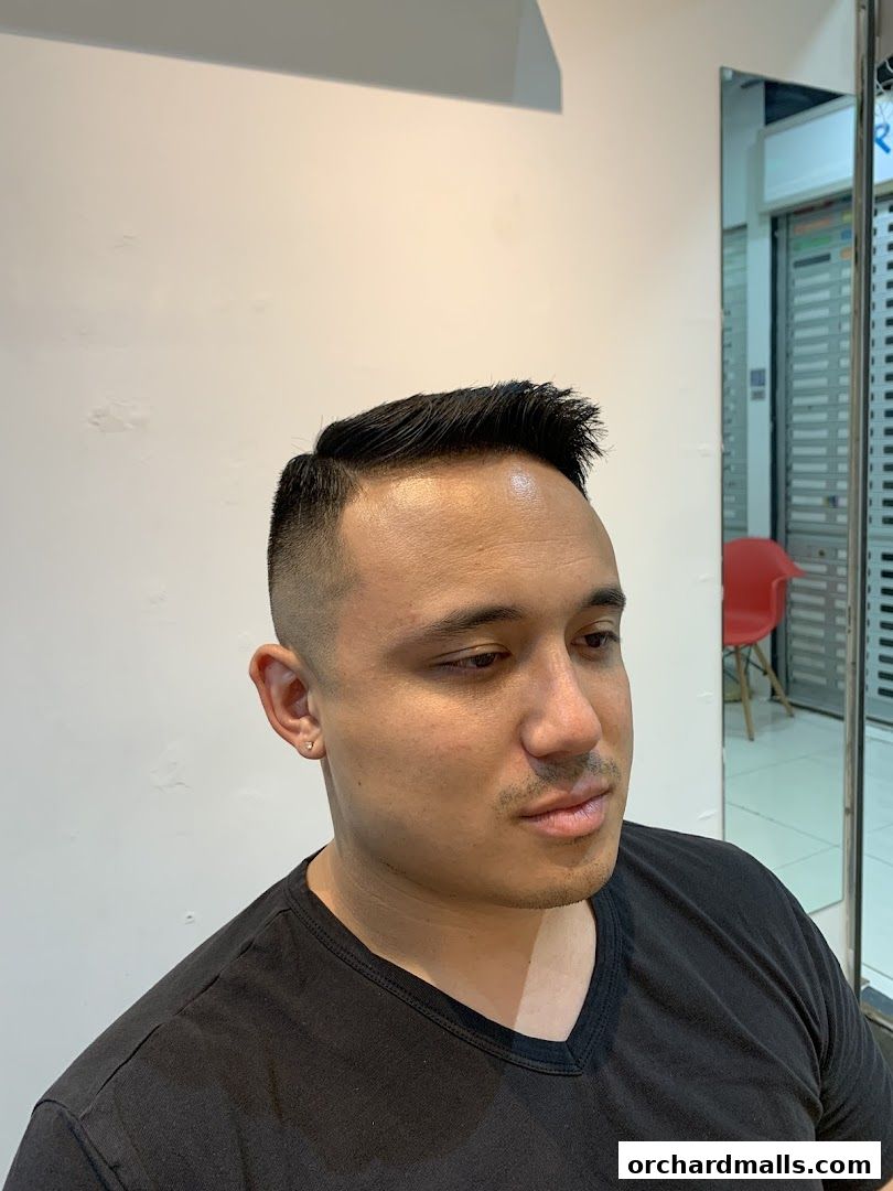 A man with a fresh fade haircut and styled hair at Holy Grail Barbershop.