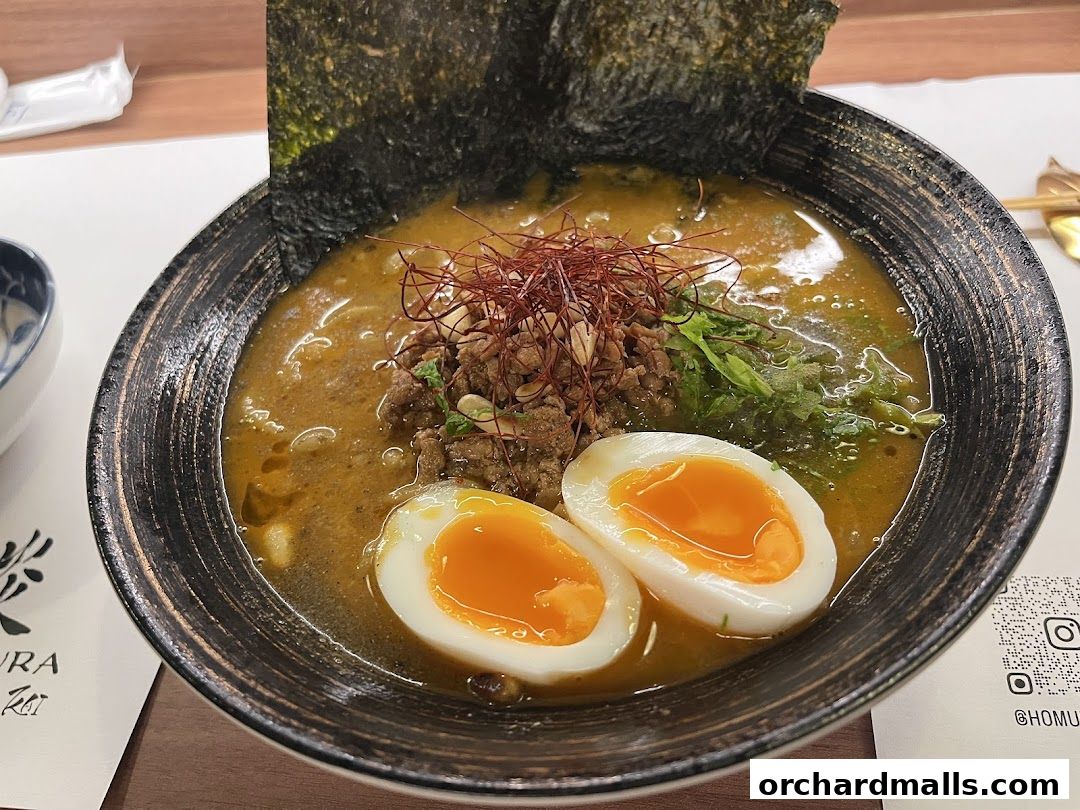 A steaming bowl of ramen with a rich broth, topped with minced meat, nori, and a perfectly cooked egg.
