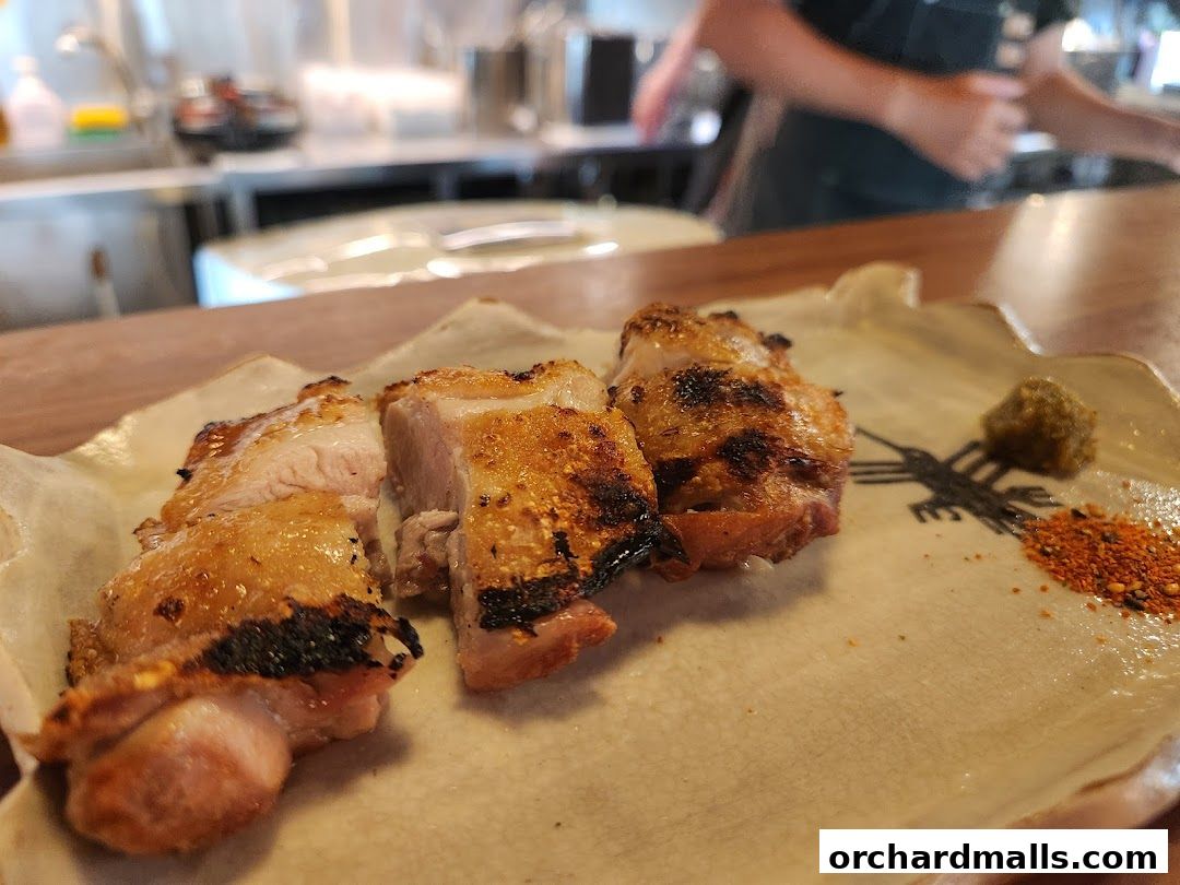Grilled chicken skewers served on a decorative plate with spices and a dollop of green paste.