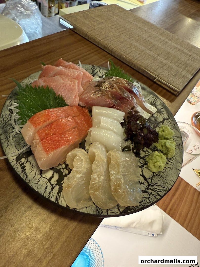A platter of assorted sashimi with wasabi and garnishes on a wooden table.
