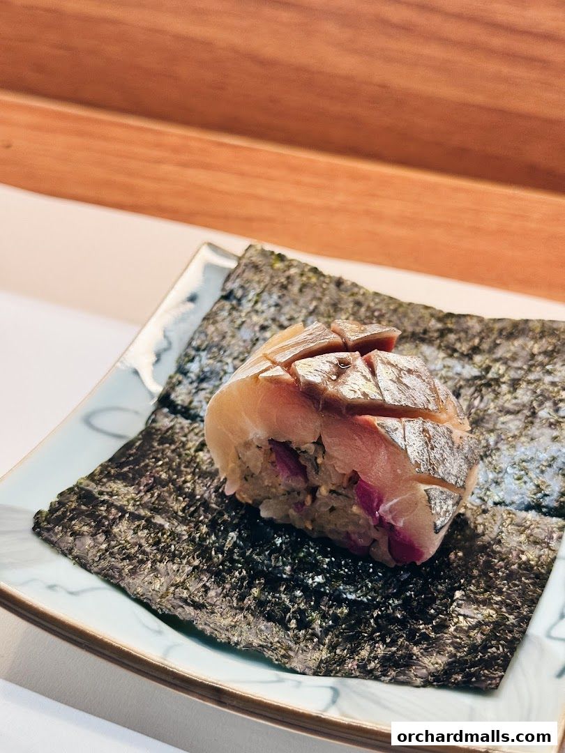 A close-up of a sushi roll with fish and rice on nori seaweed.