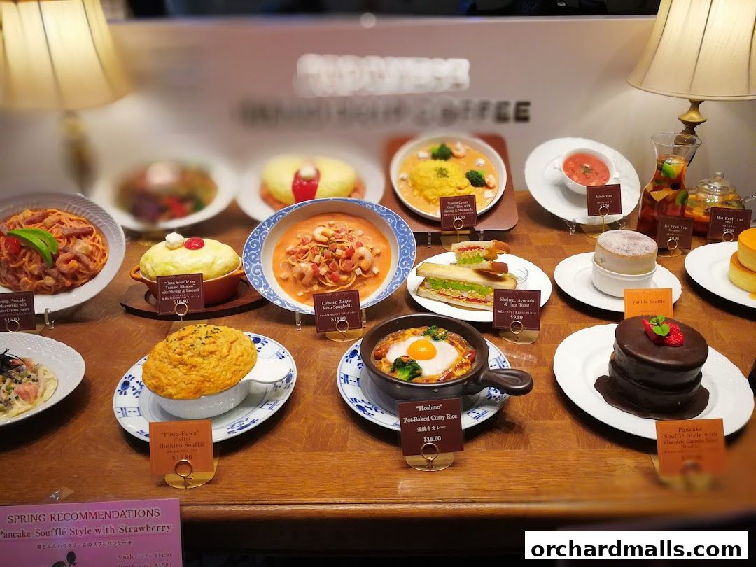 A display of various food items, including soufflés, pasta, sandwiches, and drinks, in a shop window.