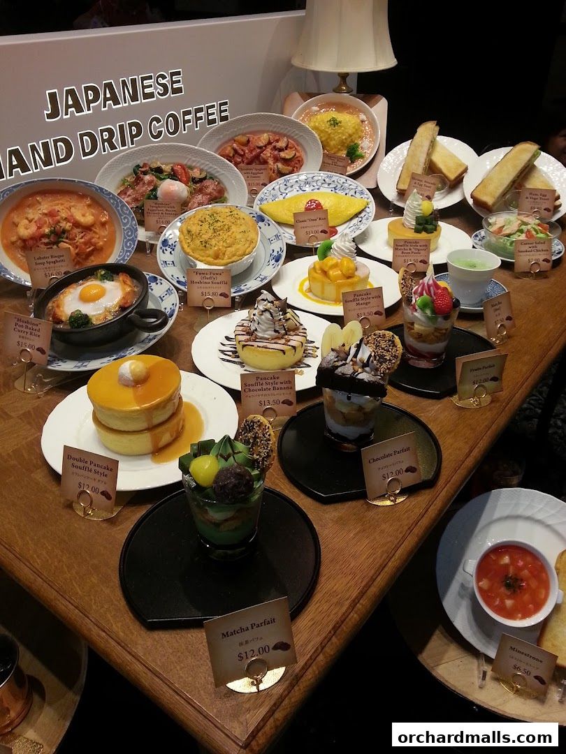 A display of various Japanese-style food and dessert items, including pancakes, parfaits, and pasta.