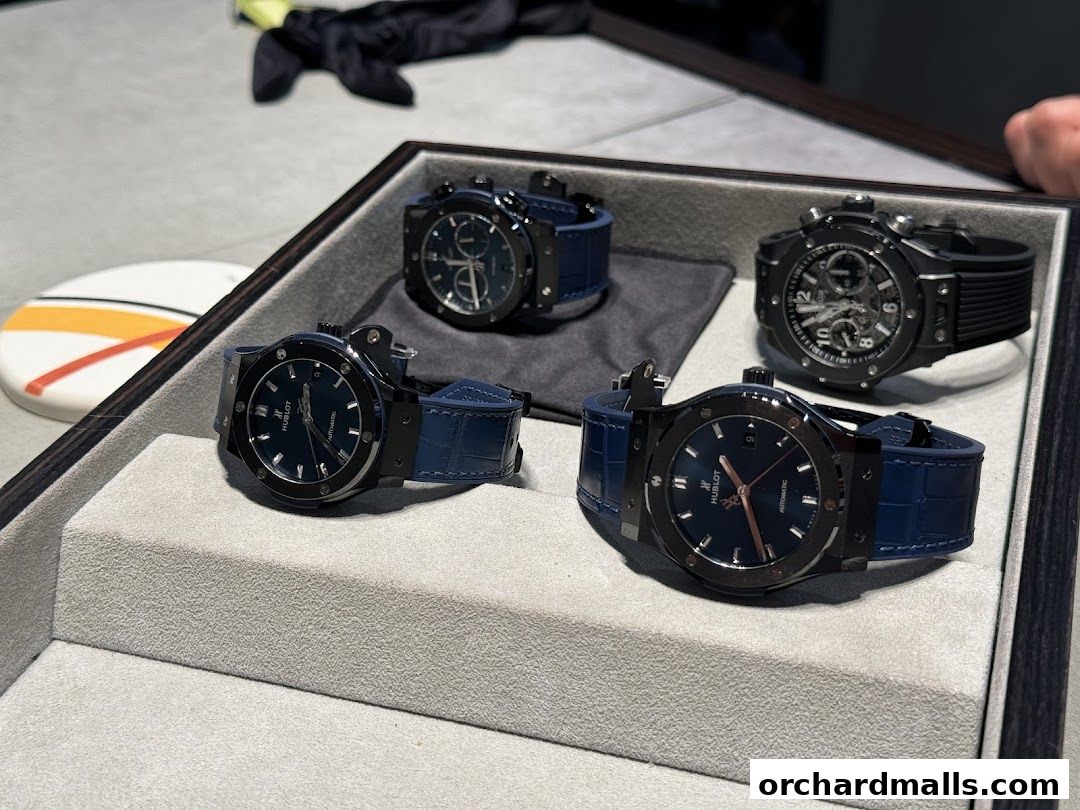 A display of four luxury Hublot watches with blue leather straps and black casings.
