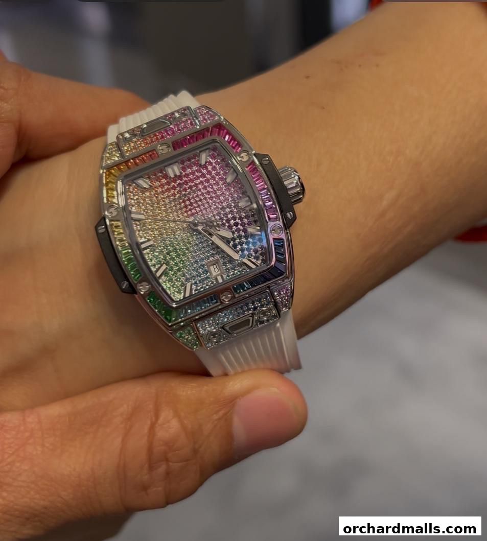 A close-up shot of a person wearing a luxurious Hublot watch adorned with colorful gemstones.