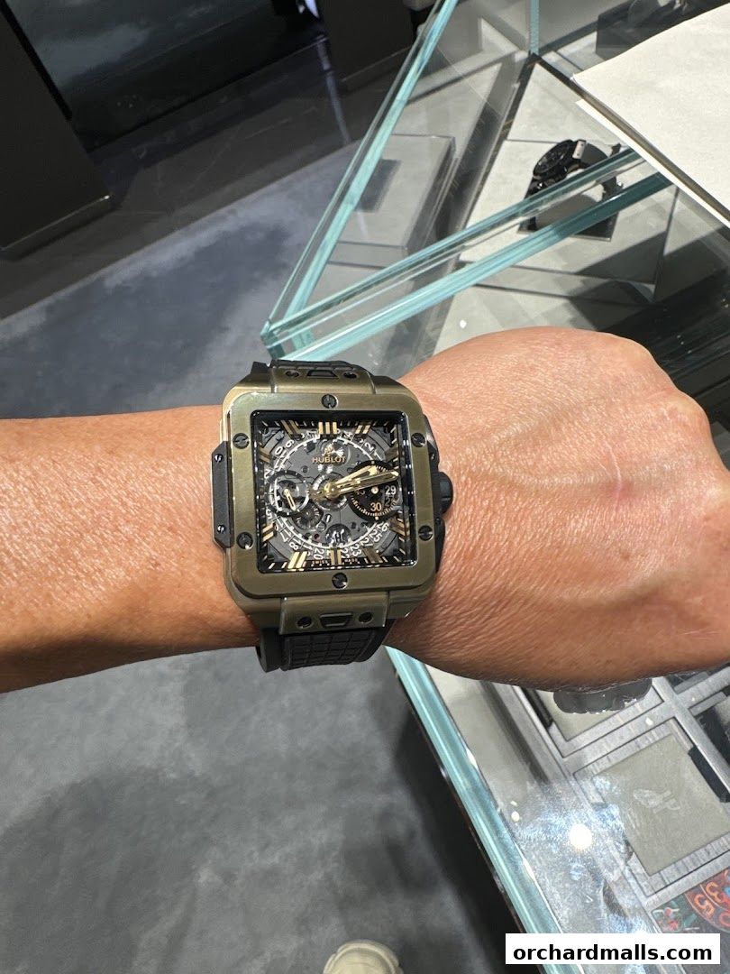 A person wearing a stylish Hublot watch with a unique bronze-colored case.