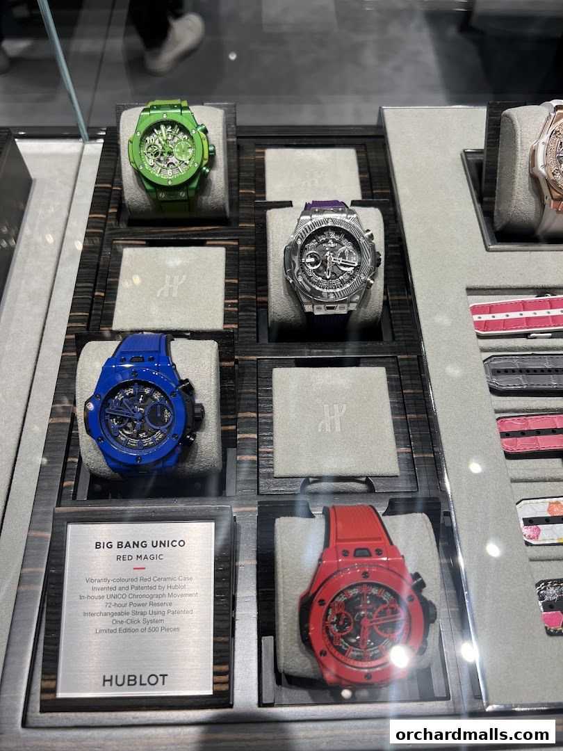 Display of colorful Hublot watches, including a red Big Bang Unico, in a luxury boutique.