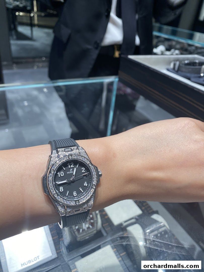A person wearing a diamond-encrusted Hublot watch with a black strap.