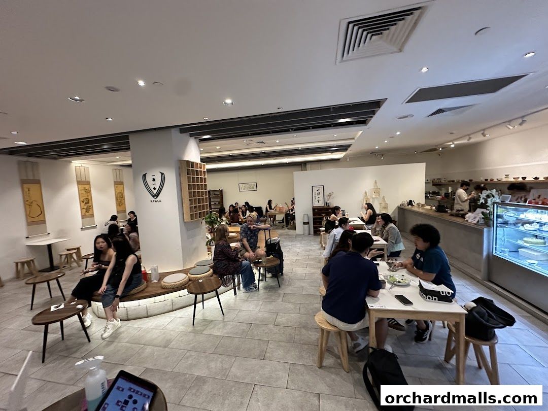 Interior of a modern cafe with customers seated at tables and a counter.