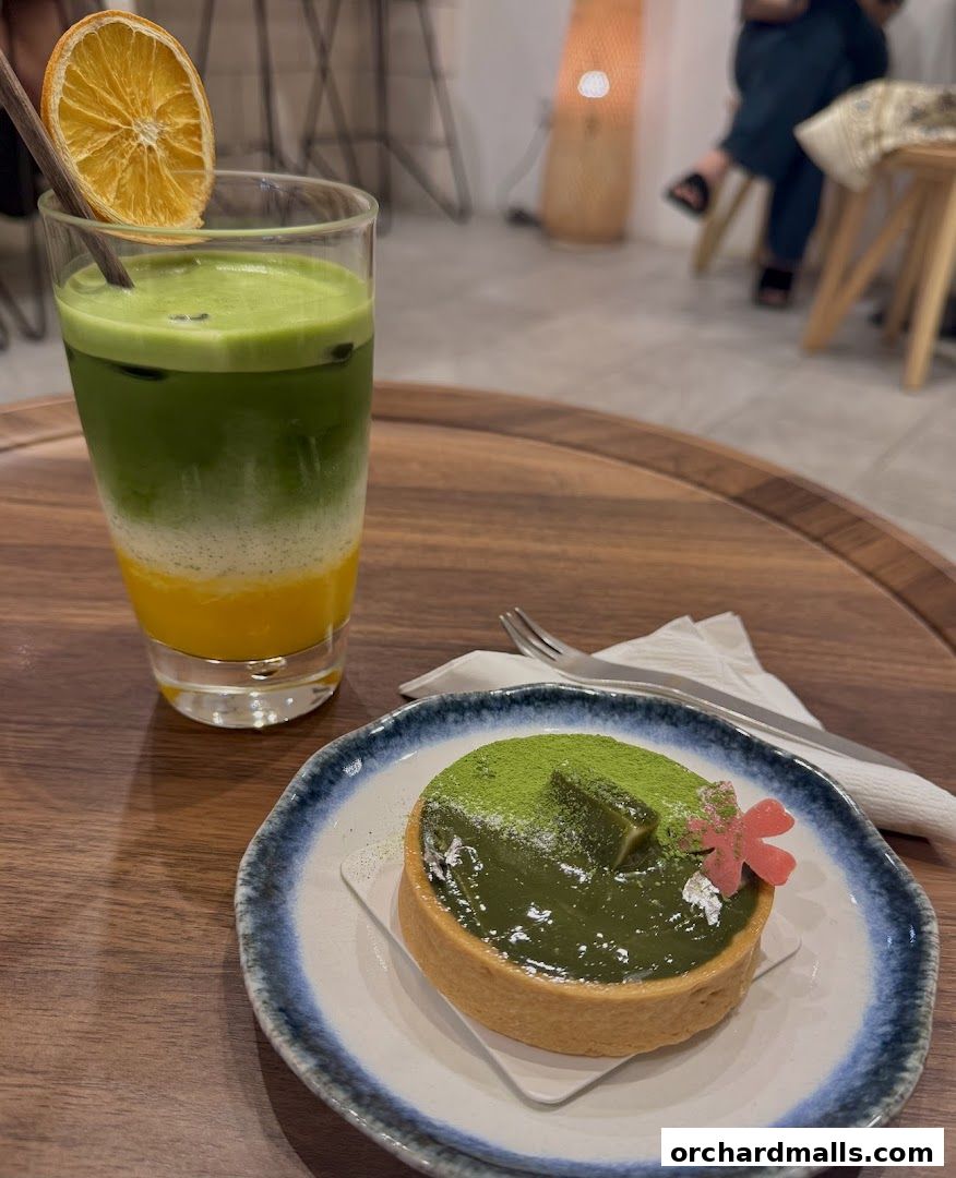 A layered matcha drink and a matcha tart on a wooden tray.