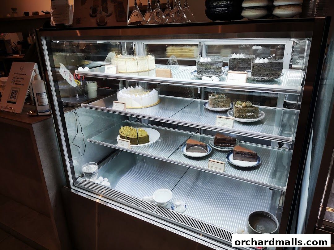 A display case filled with various cakes and desserts at Hvala Takashimaya.