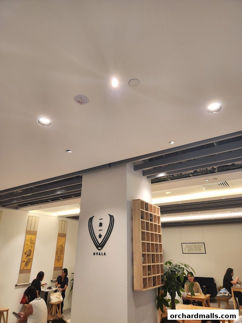 Interior of a cafe with people seated at tables and a logo on the wall.