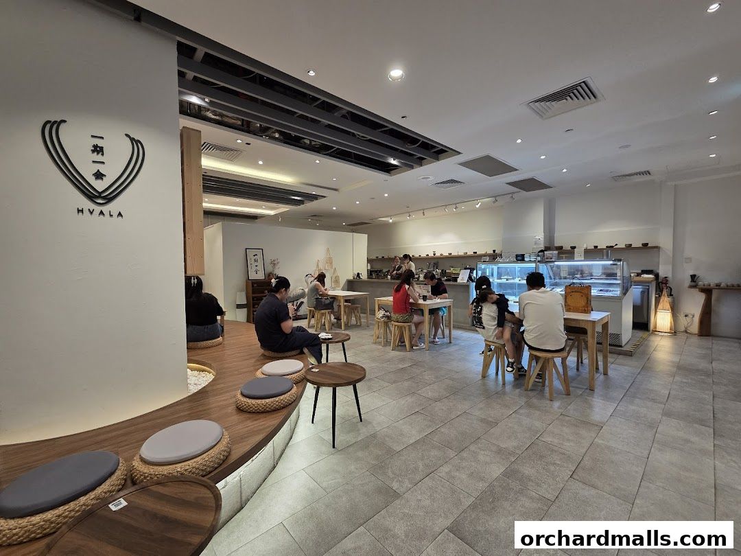 Interior of Hvala Takashimaya cafe with customers seated at tables and on floor cushions.